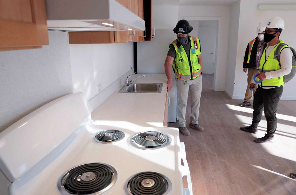 James E. Roberts-ObayasHi Corp. Superintendent Devin Blackwood (left) looks over a kitchen outfitted with electrical appliances in an apartment at the Casa Adelante apartments on Folsom Street in San Francisco in December 2020. While the Bay Area Air Quality Management District is not requiring all-electric stoves, it is focused on electrifying water heaters and furnaces.