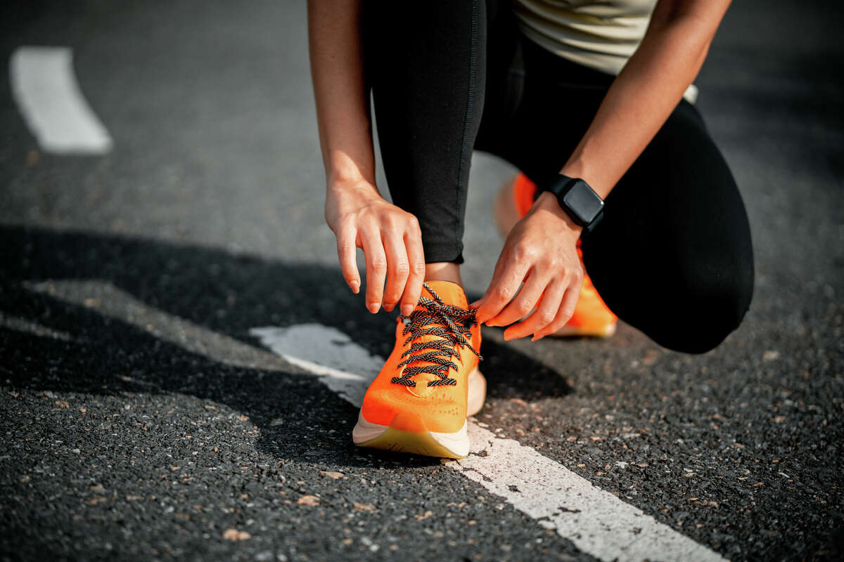 Running shoes. Woman tying shoe laces. Closeup of female sport fitness runner getting ready for jogging outdoors on forest path in late summer or fall. Jogging girl exercise motivation heatlh and fitness.