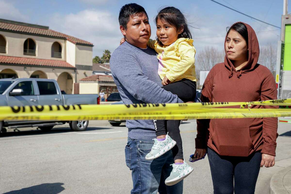 Malaquias Humberto Cruz Santiago and his wife Loida Cruz Hernandez stand with their daughter Lecni Cruz, 5, near the Pajaro River Bridge as they wait for updates about when their family can return home in Pajaro.