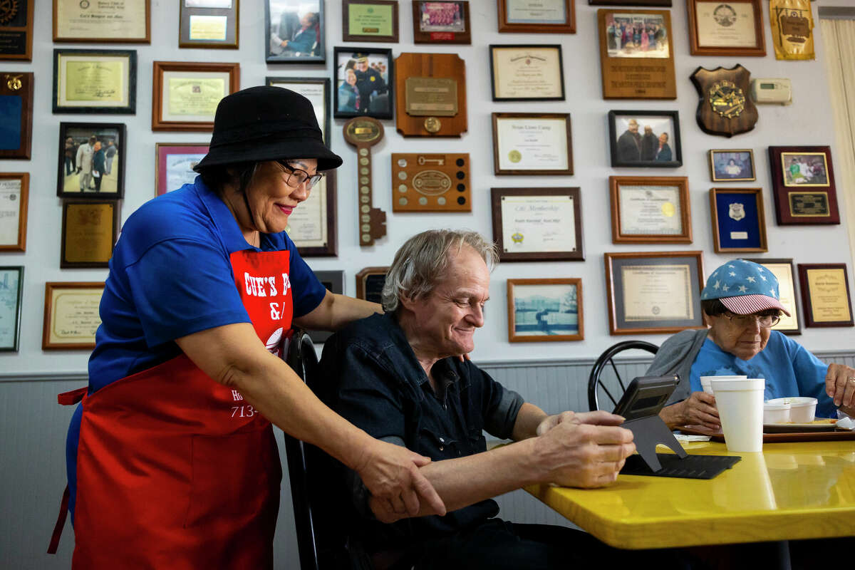 Cuc “Mama Cue” Roberts greets a customer at Cue’s Hamburgers on Friday, March 10, 2023.