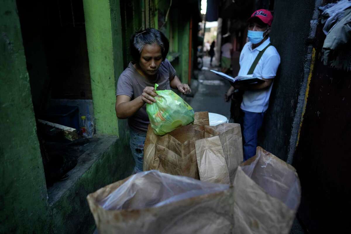 Residents place segregated garbage on a cart along the streets of Malabon, Philippines on Monday Feb. 13, 2023. Food waste emits methane as it breaks down and rots. Waste pickers are helping set up systems to segregate and collect organic waste, and establishing facilities to compost it.