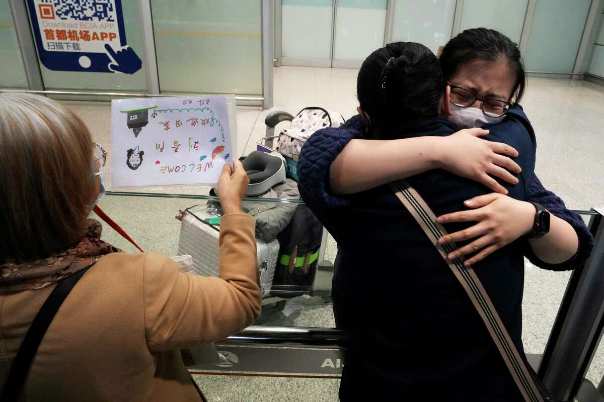 A woman hugs another returning on one of the few overseas flight arriving at the Beijing Capital International Airport in Beijing, Tuesday, March 14, 2023. China will reopen its borders to tourists and resume issuing all visas Wednesday after a three-year halt during the pandemic as it sought to boost its tourism and economy.