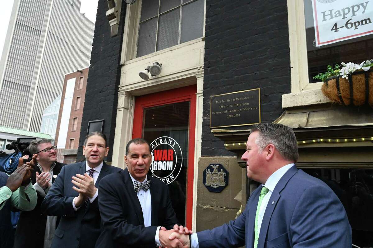 Former Gov. David Paterson, center, is congratulated by Albany County Executive Dan McCoy, right, during a dedication ceremony to name the War Room Tavern building in Gov. Paterson’s honor on Friday, March 17, 2023, in Albany, N.Y. TheEagle St. restaurant and bar is located across from Albany Capital Center.