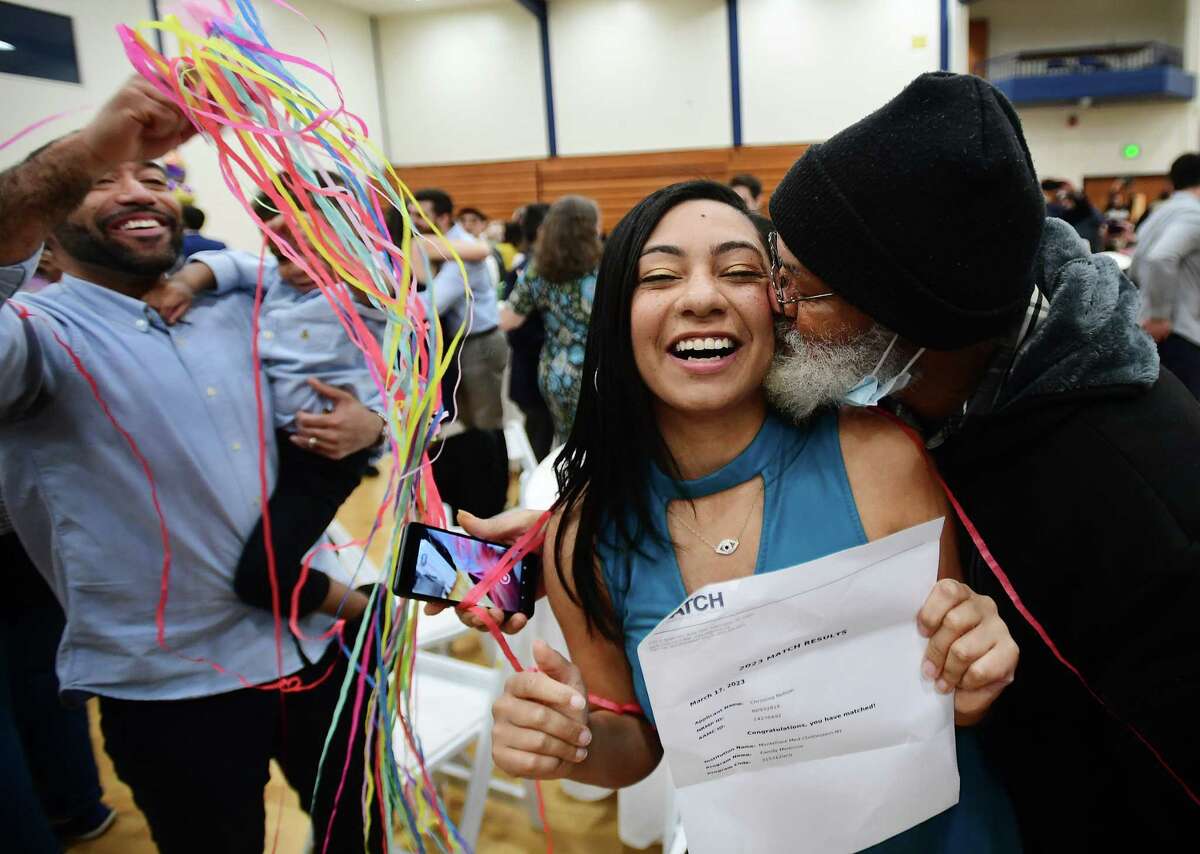 Medical student Christina Nelson, of New Haven, gets a kiss from her father, Dave Gomez, as her brother, Nathaniel Koonce, left, celebrates her medical residency match with Montefiore Medical Center, in The Bronx, during Match Day at Quinnipiac University in Hamden, Conn on Friday, March 17, 2023. Ninety-six med students received their residency matches during the annual event.