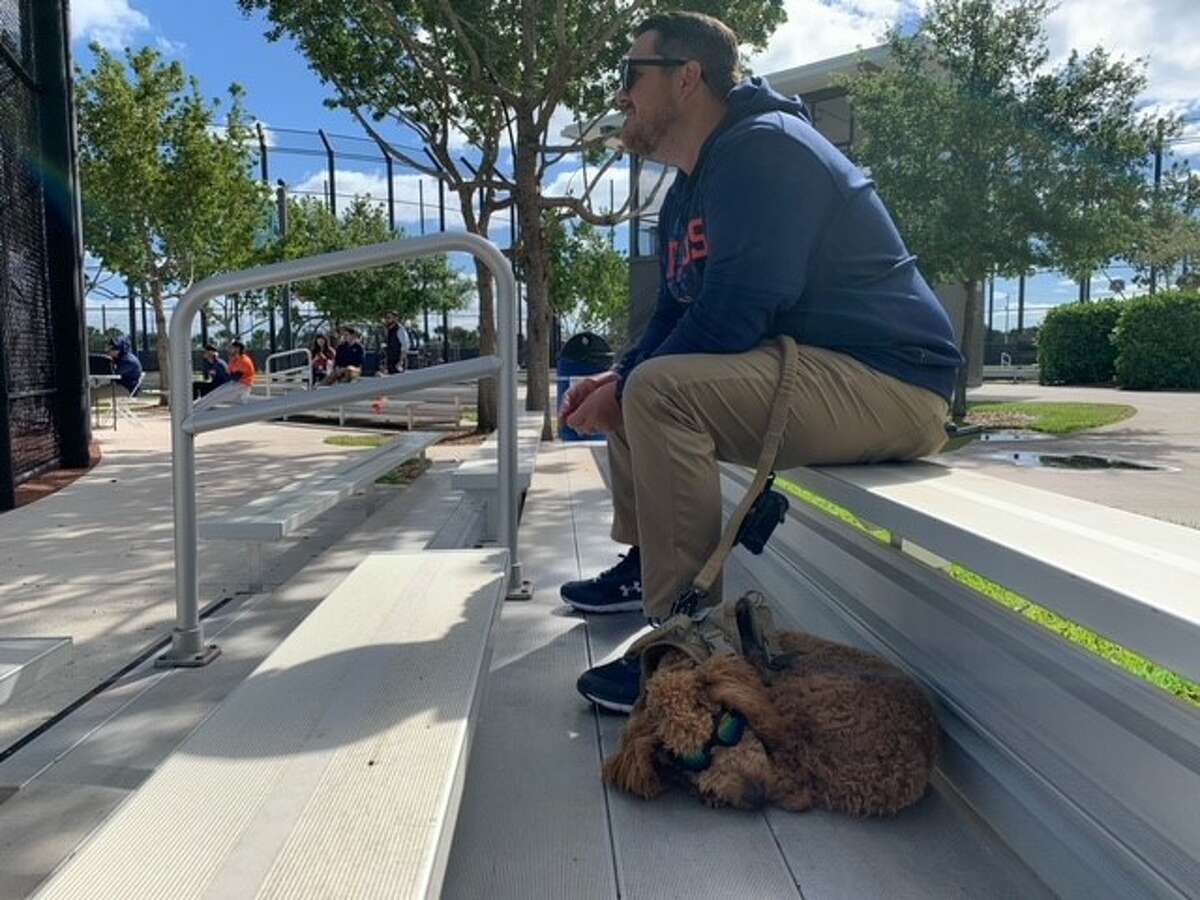 A 7-month-old Goldendoodle named Chewbacca — Chewy, for short — sits with Justin McKissick, a mental skills coach for the Astros at spring training on Wednesday, March 15, 2023 in West Palm Beach, Fla.