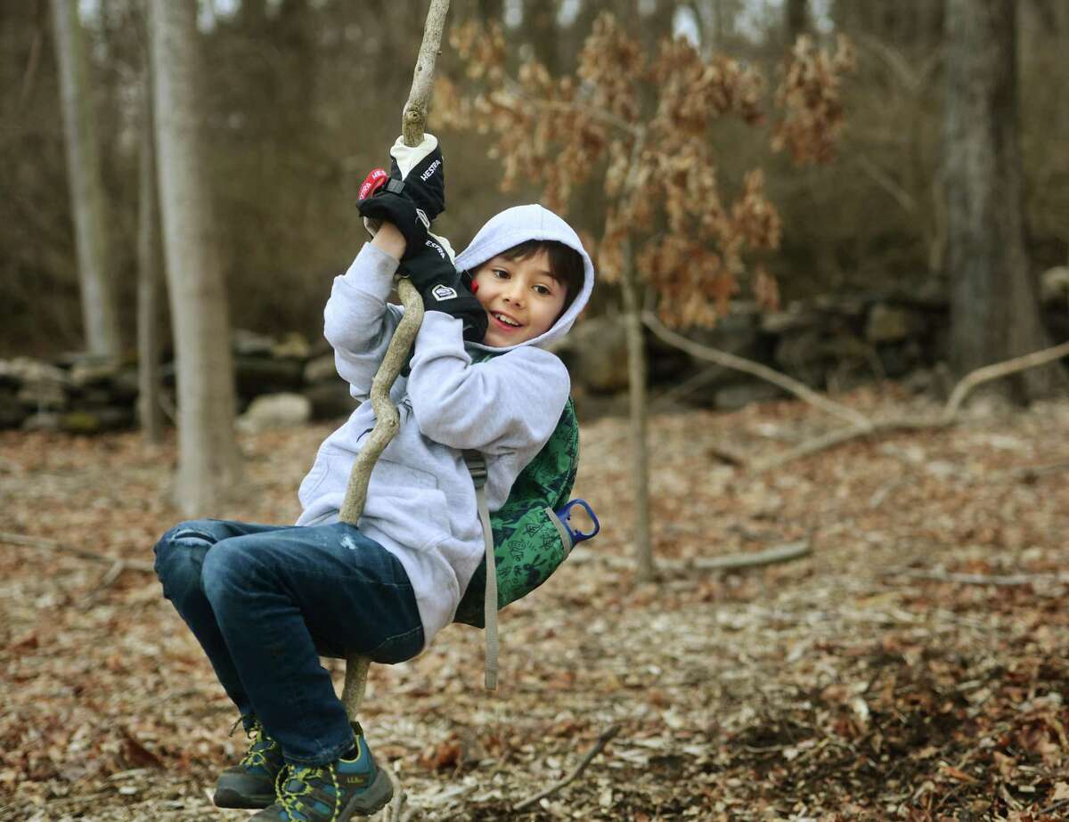 Finn Yardis, 8, of Greenwich, swings on an invasive vine at Converse Brook Preserve during Laurel Scarlata's monthly Greenwich Nature Day immersion program for kindergarten thru fifth graders in Greenwich, Conn on Saturday, March 18, 2023.