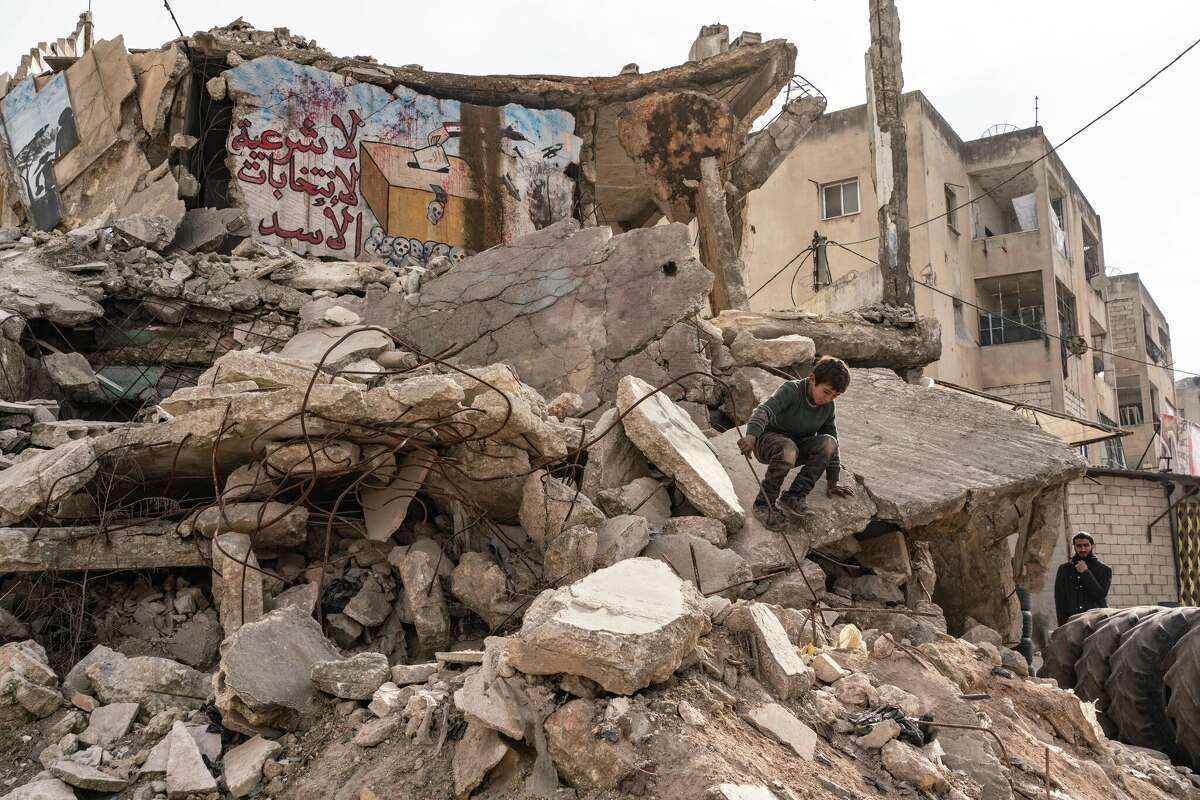 IDLIB, SYRIA - FEBRUARY 27: Yazan, 10-years-old, climbs down from a destroyed building with writing on it that says there is no legitimacy of Assad's elections on February 27, 2023 in Idlib, Syria. According to locals more than two million people who have been displaced because of war lived in the northwest of Syria before the recent earthquakes. A 7.8-magnitude earthquake hit near Gaziantep, Turkey, in the early hours of February 6, followed by another 7.5-magnitude tremor just after midday. The quakes caused widespread destruction in southern Turkey and northern Syria and has killed more than 40,000 people. (Photo by Abdulmonam Eassa/Getty Images)