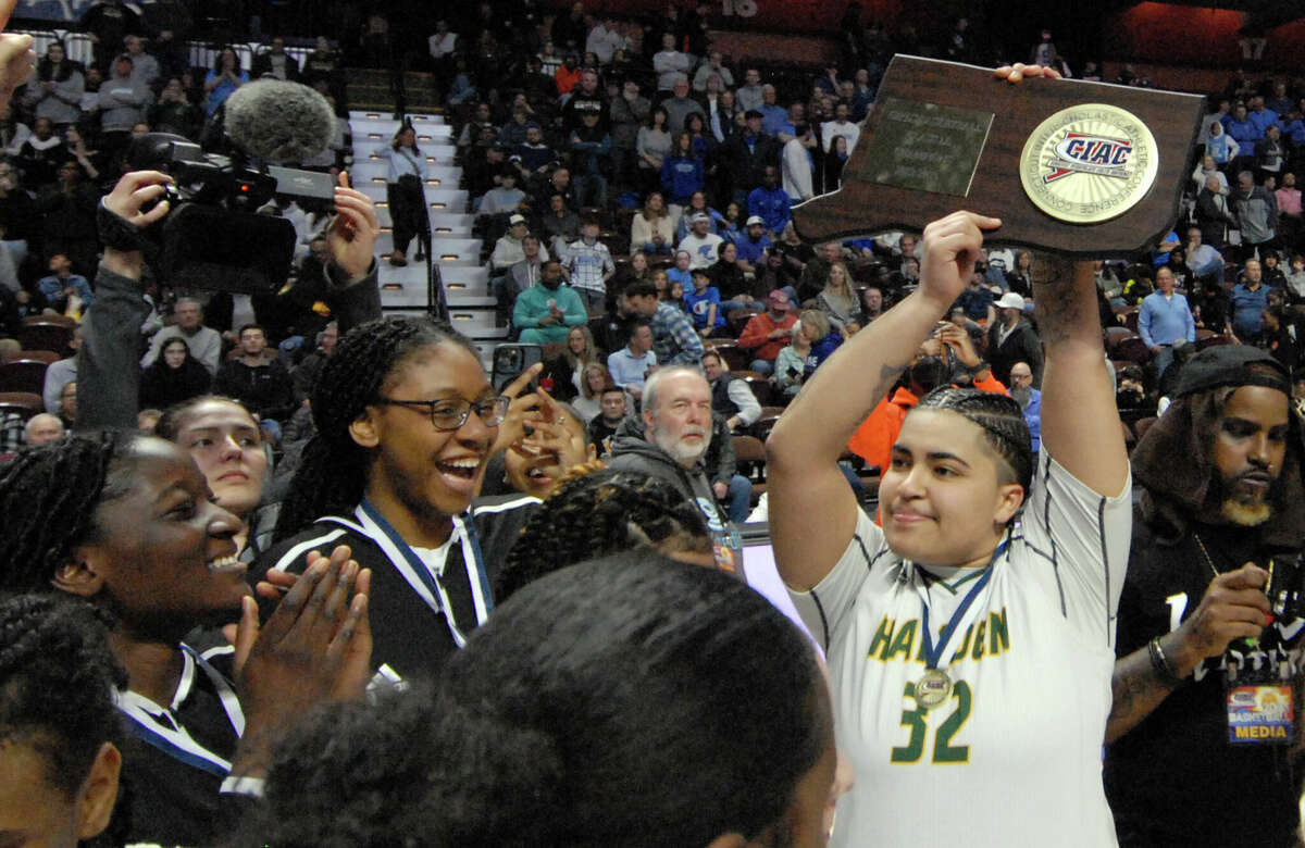 Hamden's Gianna Robert (32) holds up the championship plaque as the team celebrates their win over Fairfield Ludlowe in CIAC basketball championship basketball at Mohegan Sun Arena in Uncasville, Conn., on Saturday March 18, 2023.