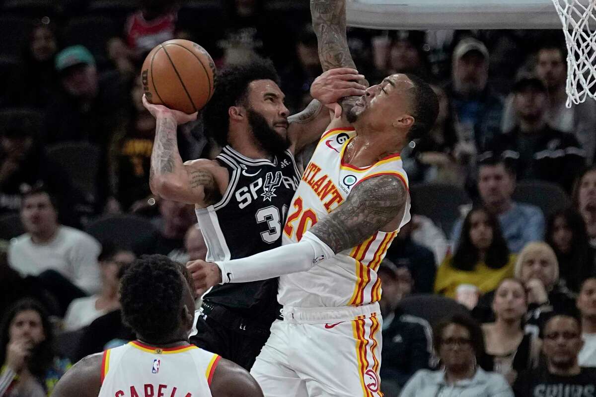 San Antonio Spurs forward Julian Champagnie, top left, drives to the basket against Atlanta Hawks forward John Collins (20) during the first half of an NBA basketball game in San Antonio, Sunday, March 19, 2023.