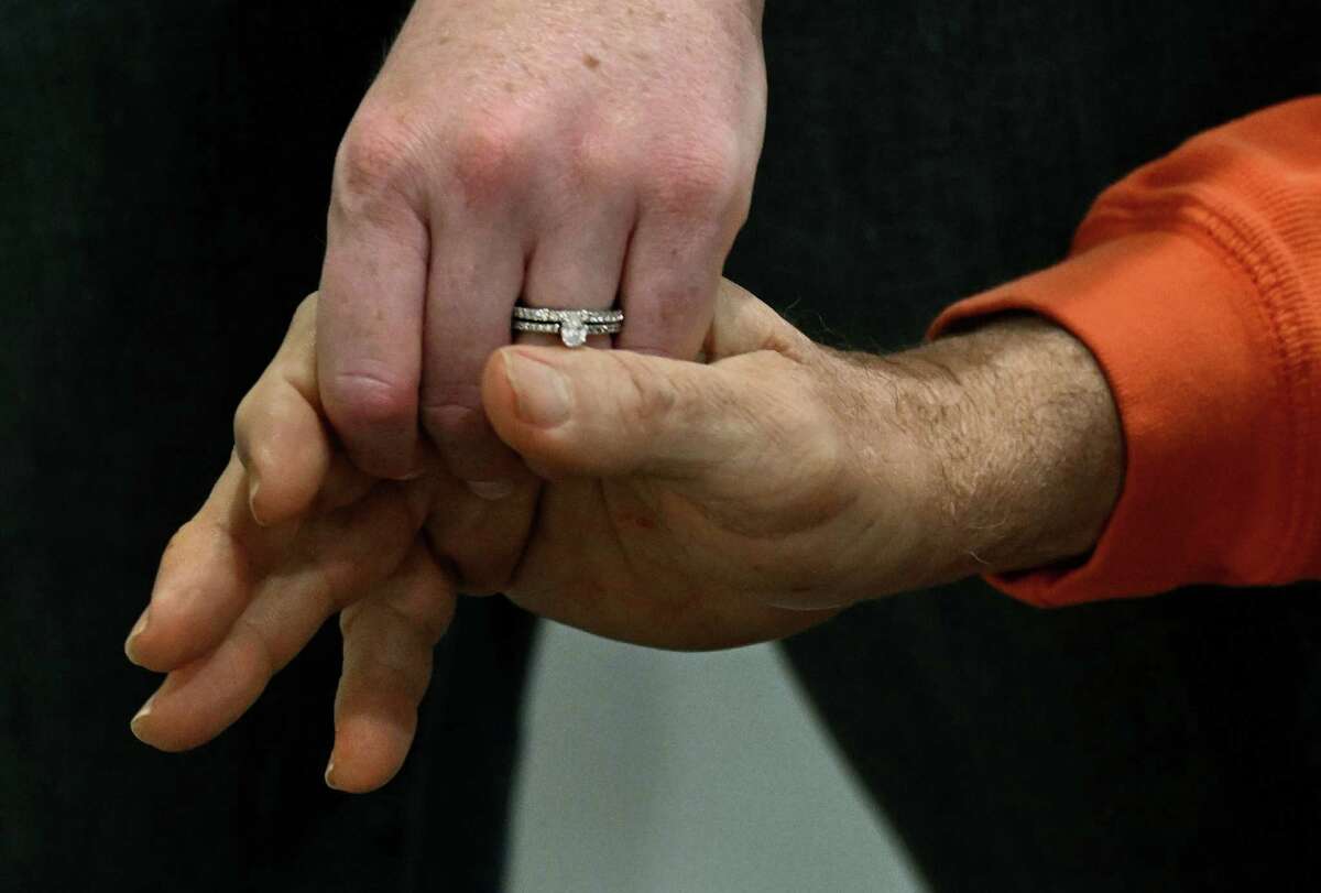 Kathryn, recently wed, and her father, Doug, hold hands during their visit.