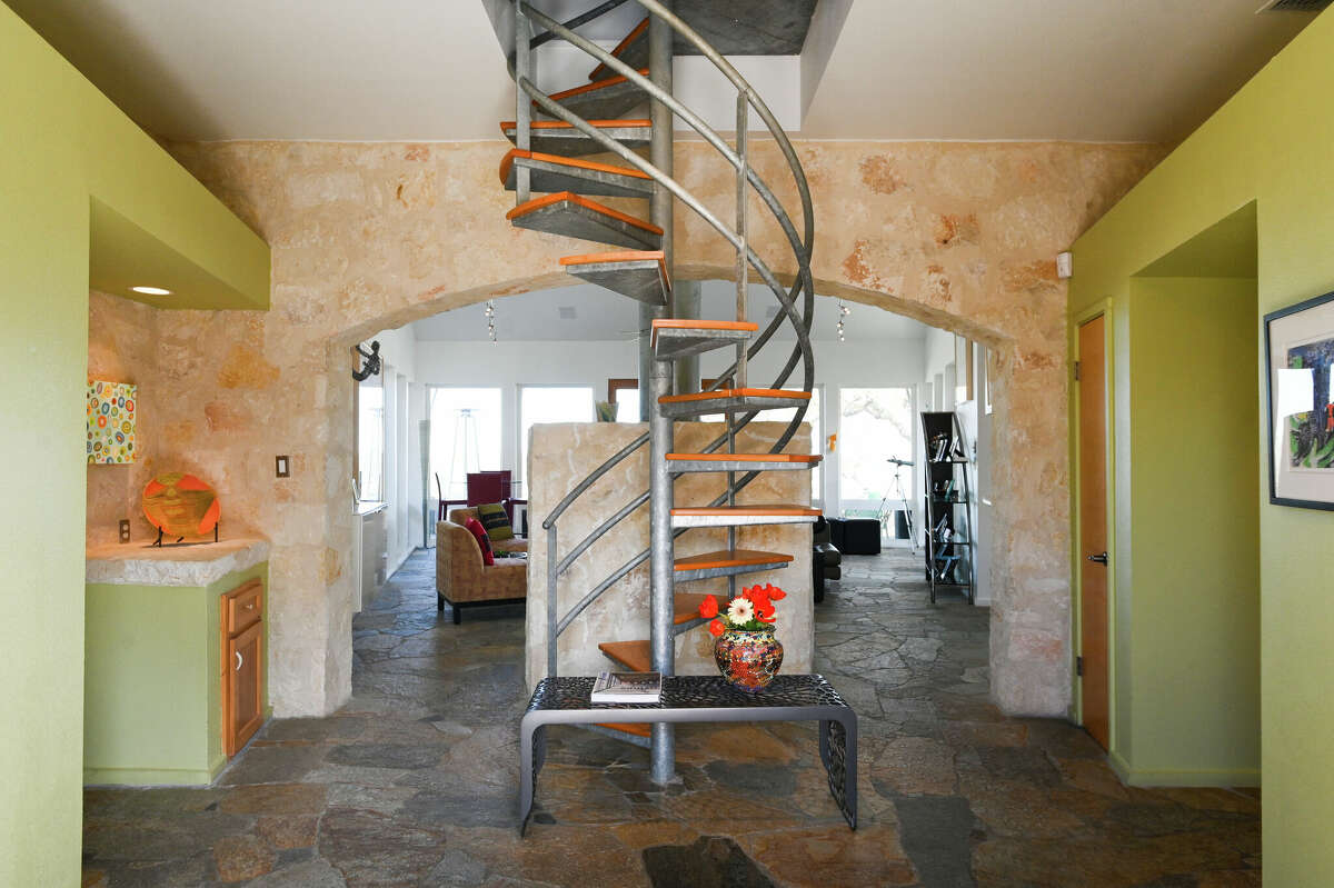 Upon entering the front door, visitors are blocked from seeing the expansive views by a spiral staircase and a large standalone limestone fireplace.