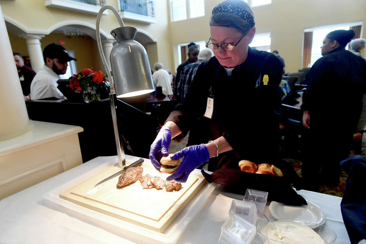 Karen Monk sets out sliders for guests to enjoy during a BBQ and Bourbon social event at Calder Woods in Beaumont Tuesday. Photo made Tuesday, March 21, 2023 Kim Brent/Beaumont Enterprise