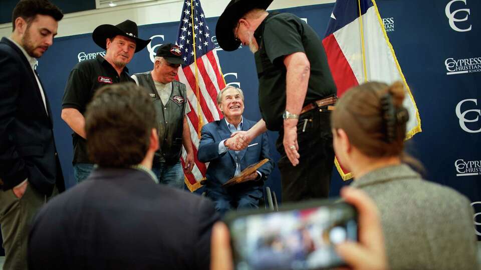 Gov. Greg Abbott smiles as he meets members of Taylor’s Organization after a rally about school vouchers Tuesday March 21, 2023, at Cypress Christian School in Houston. The group gave him an award they made. Abbott and his allies say the voucher effort is about school choice. Critics say they are private school vouchers that allow people to take money out of the public school system to benefit private schools.