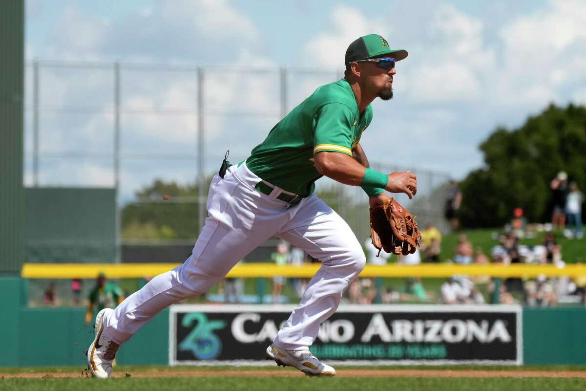 Oakland Athletics third baseman Jace Peterson, left, chases down a grounder  as Athletics shortstop Aledmys Diaz, right, looks on during the first  inning of a spring training baseball game against the San