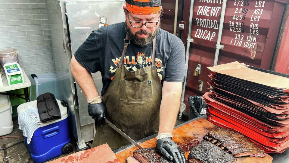 Willow Villarreal cutting brisket at Willow's Texas BBQ pop-up at Two Headed Dog bar