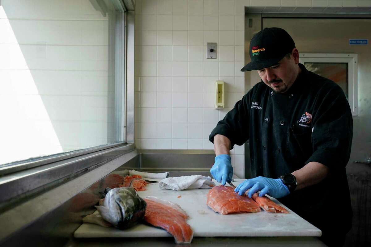 Luis Alvarenga, executive chef at Scoma's, cleans a farm-raised salmon in San Francisco, Monday, March 20, 2023. On April 7, the Pacific Fishery Management Council, the regulatory group that advises federal officials, will take action on what to do about the 2023 season for both commercial and recreational salmon fishing.