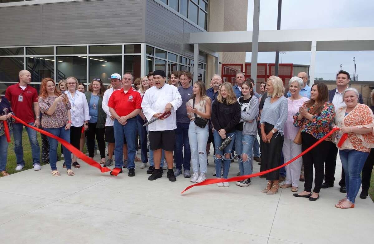 Lumberton High School senior and culinary student Tin Vo, center, cuts the ribbon for the school's new Career and Technical Education building. Photo taken March 23, 2023. Photo by Olivia Malick/ The Enterprise