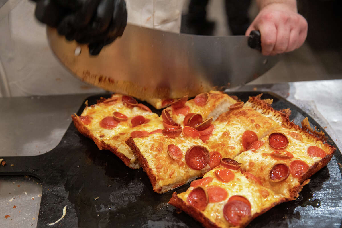 Kitchen staff Sydd Urgola cuts up a Detroit-style pizza at Pizzeria da Laura in Berkeley, Calif. on March 23, 2023.