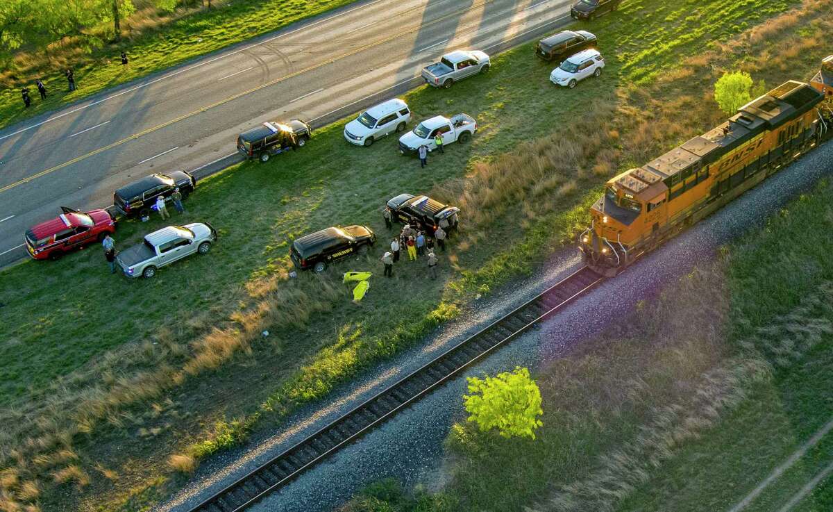 Officials investigate the scene where migrants were found trapped in a train car, Friday, March 24, 2023 in Ulvalde, Texas. Union Pacific railroad said in a statement that the people were found in two cars on the train traveling east from Eagle Pass bound for San Antonio. (William Luther/The San Antonio Express-News via AP)