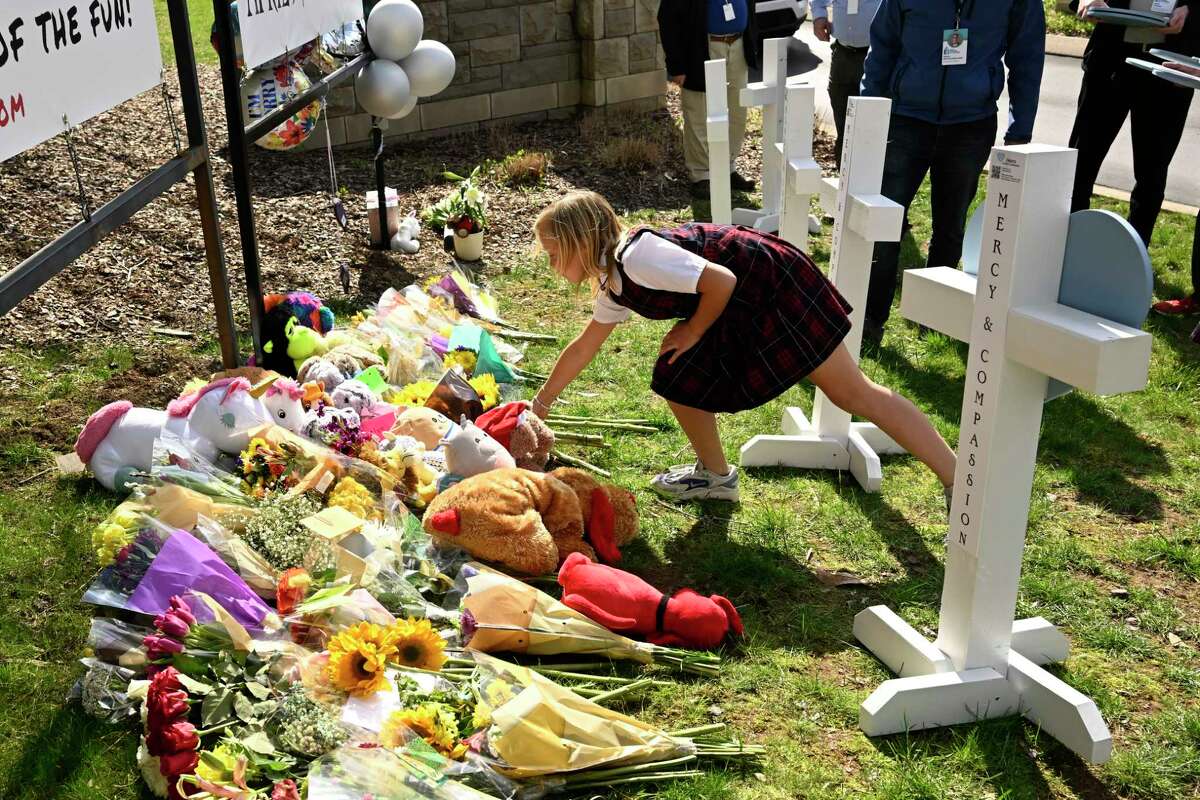 A young girl places an item at a growing memorial,Tuesday, March 28, 2023, in Nashville, at an entry to Covenant School for the victims of Monday' shooting.