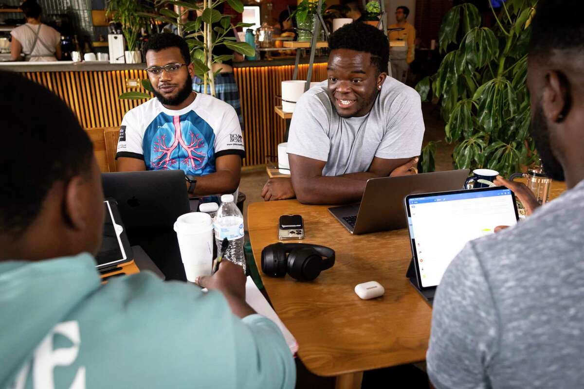 First-year student Rapha Onyeka, right, chats with fellow members of the Baylor College of Medicine chapter of Black Men in White Coats at Brass Tacks coffee shop on Sunday, March 26, 2023.