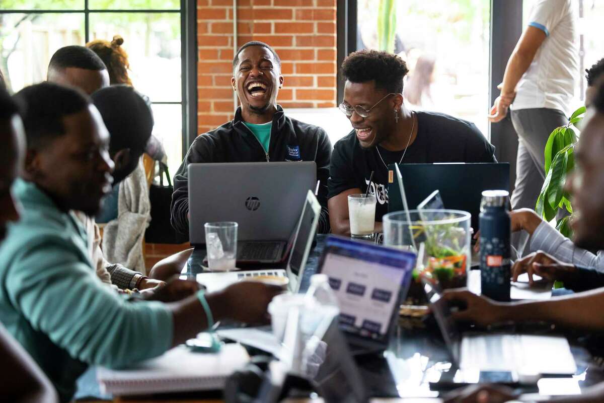 Ebubechi Adindu, left center, and Anthony “Duru” Duruewuru, right center, laugh during a casual gathering of members of the Baylor College of Medicine chapter of Black Men in White Coats at Brass Tacks coffee shop on Sunday, March 26, 2023. Both students hope to continue their studies in orthopedic surgery.