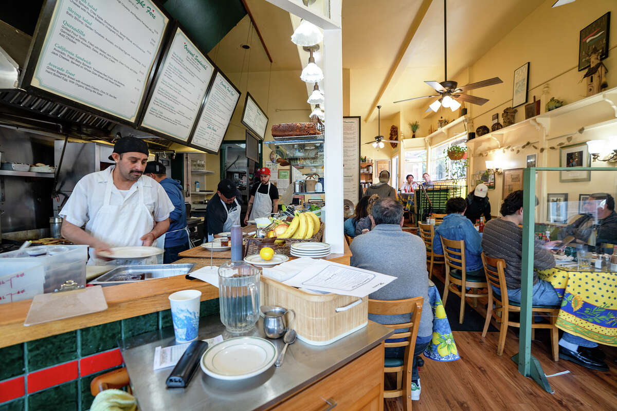 Diners eat while kitchen staff prepare food inside of Mama's on Washington Square in San Francisco on March 25, 2023.