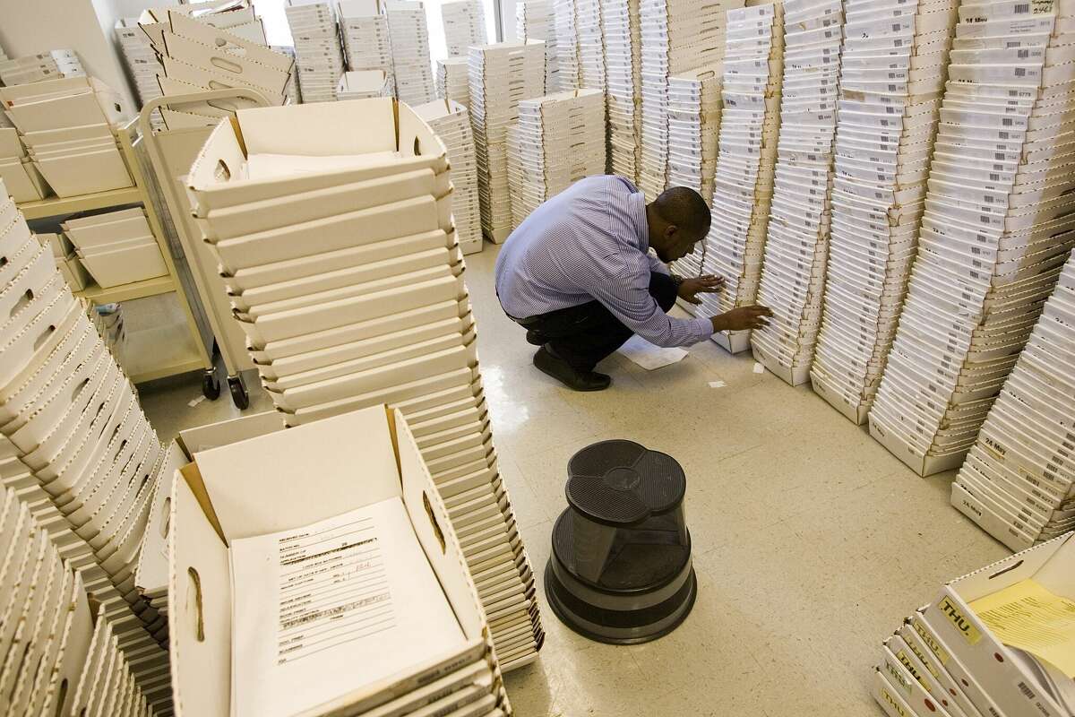 A worker at the United States passport agency in San Francisco looks through boxes of backlogged passport applications in July 2007.