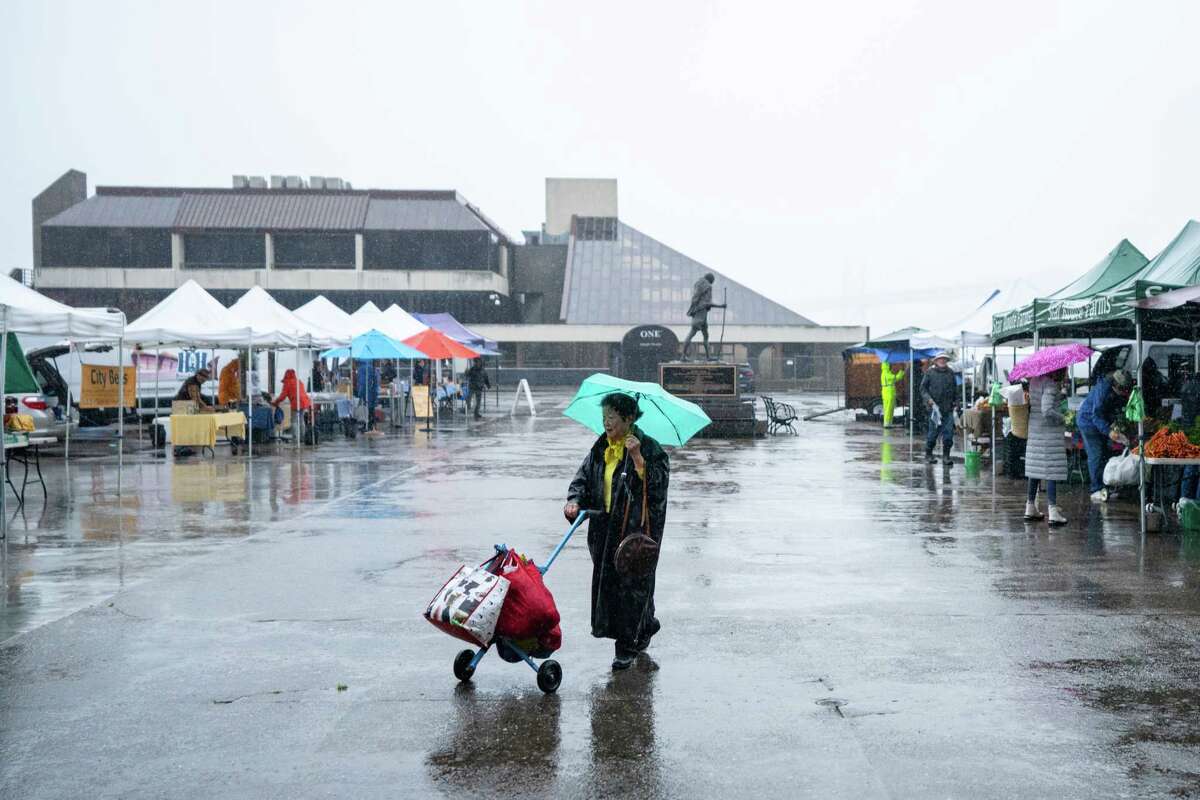 12月，渡轮大厦农贸市场的一位顾客带着他们的杂货在雨中前行。市场报告说，在多雨的冬季，人流量急剧下降。