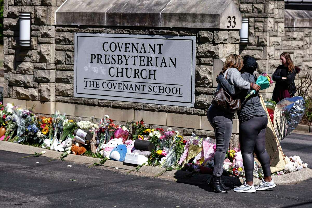 FILE - Two women hug at a memorial at the entrance to The Covenant School on Wednesday, March 29, 2023, in Nashville, Tenn. Family and friends of Michael Hill, the 61-year-old custodian killed during a shooting on Monday, March 27, at a small Christian elementary school in Nashville, gathered on Tuesday, April 4, to mourn their loss. Hundreds turned out for the funeral service at Stephens Valley Church, where pastor Jim Bachmann said the hearts of the congregation were aching for the man they called “Big Mike.”