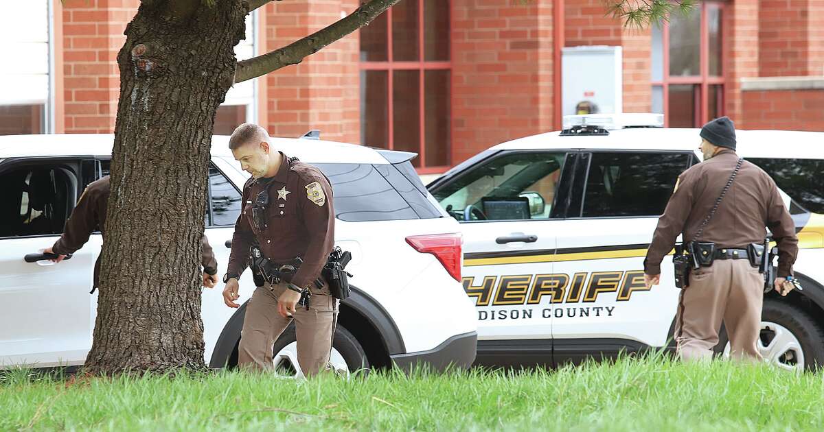 Madison County Deputy Sheriffs crowd the apron in front of Alton fire Station  No. 2 Wednesday after an officer fired at least one shot at charging dogs. The deputy was chased by the dogs while attempting to serve process papers to a nearby house. 