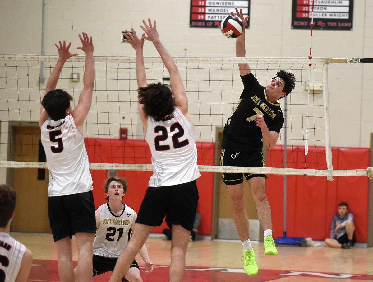 Joel Barlow's Alex Llach (7) goes up for a shot while New Canaan's William Webster (22) and Jerome Roscoe (5) attempt to block during a boys volleyball match in New Canaan on Wednesday, April 5, 2023.