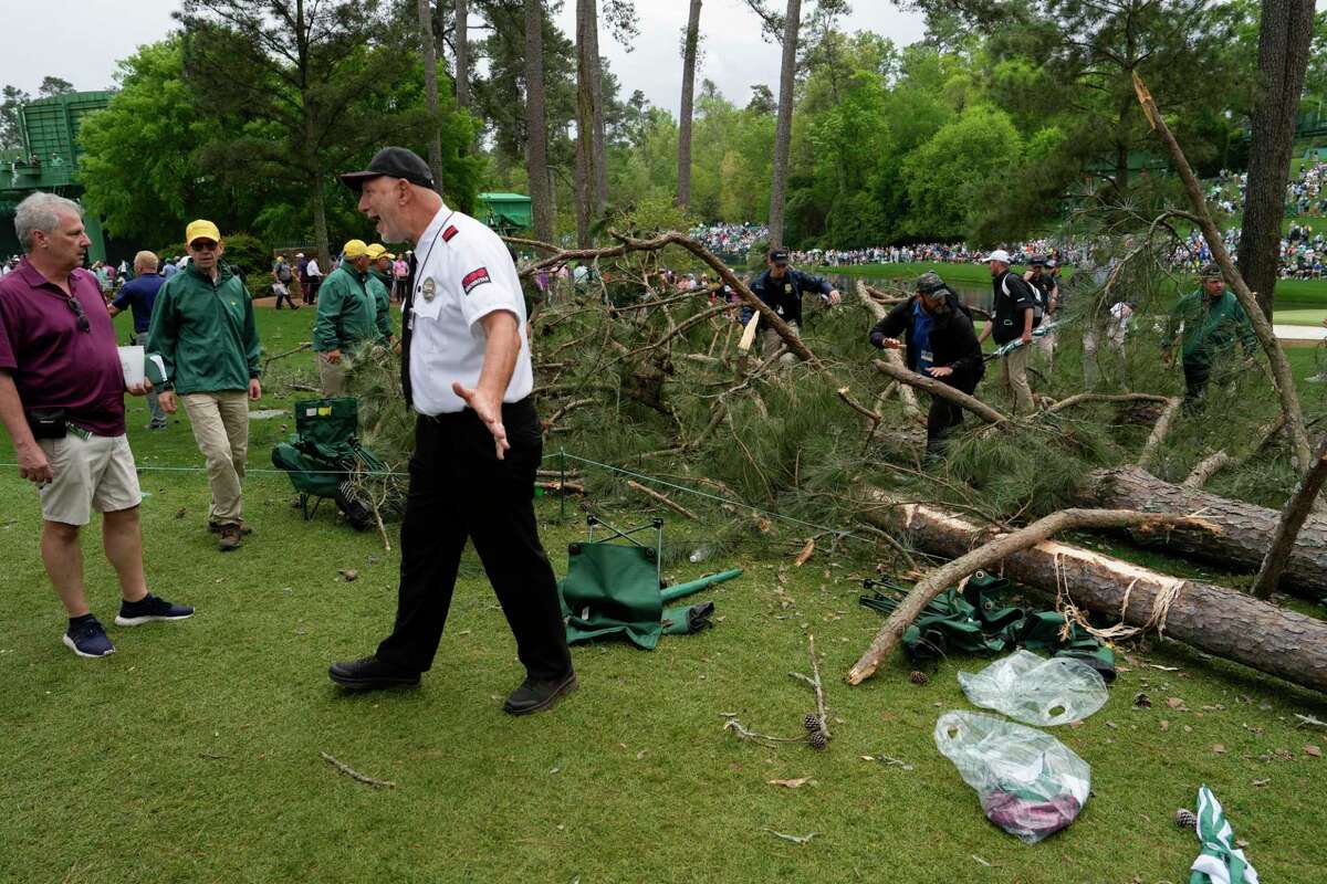 A security guard moves patrons away from trees that blew over on the 17th hole during the second round of the Masters golf tournament at Augusta National Golf Club on Friday, April 7, 2023, in Augusta, Ga.