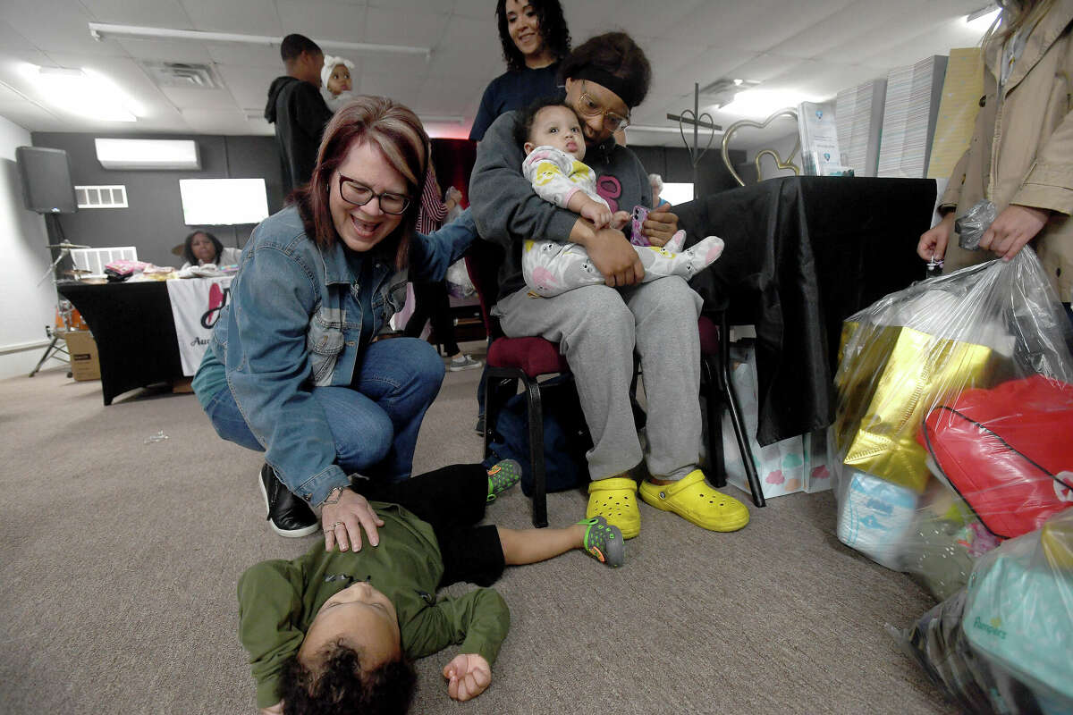 Donna Wells adds a prayer for toddler D.J. Kenebrew as his mom Marrhonda Locks, pregnant with twins, and baby sister Dessi receive prayers at the Wells of Agape station during the 2nd Annual Orange County Community Baby Shower at Destiny Church in Orange. Photo made Saturday, April 8, 2023 Kim Brent/Beaumont Enterprise