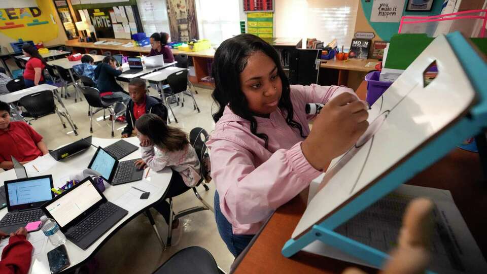 Tutor Sedaytria Hayes works with third grade students at Highland Heights Elementary on Tuesday, April 11, 2023 in Houston.