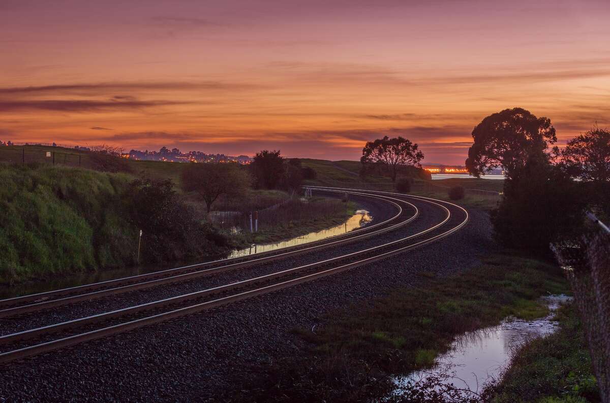 A stock image capturing railway tracks during a pastel sunset.
