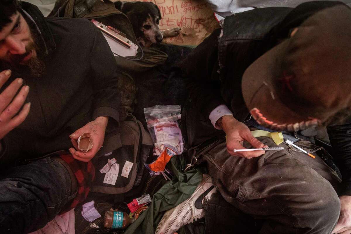 Andy Berger (left) sits with friend Spencer Gray, who prepares a fentanyl injection inside a tent in San Francisco on Jan. 10. The debate on how the city should use millions of dollars from opioid settlements in S.F.’s drug crisis is heating up.