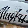 2005年8月26日星期五，阿拉斯加安克雷奇特德史蒂文斯国际机场，一名阿拉斯加航空公司的飞行员坐在飞机的驾驶舱里与地勤人员交谈。摄影师:丹尼尔·阿克/彭博新闻。