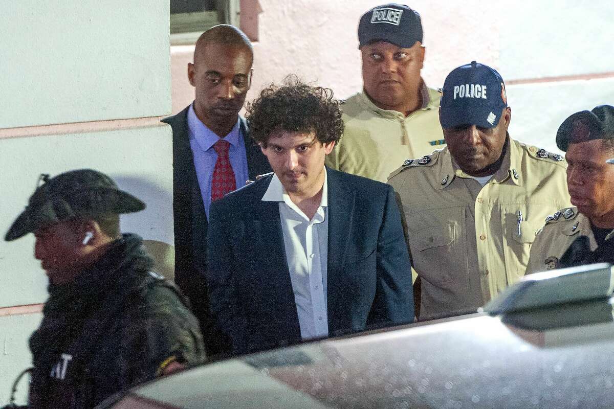 FTX founder Sam Bankman-Fried (C) is led away in handcuffs by officers from the Royal Bahamas Police Force in Nassau, Bahamas on December 13, 2022. Bankman-Fried was hit with multiple criminal charges for the largest financial frauds in US history.  (Photo by Mario Duncanson/Getty Images)