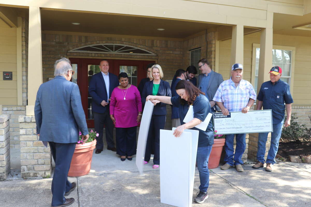 Texas General Land Office Communications Director Brittany Eck hands out large checks for local officials and representatives of state officials to hold for a photo on April 14, 2023 at Sunlight Manor Apartments in Beaumont.