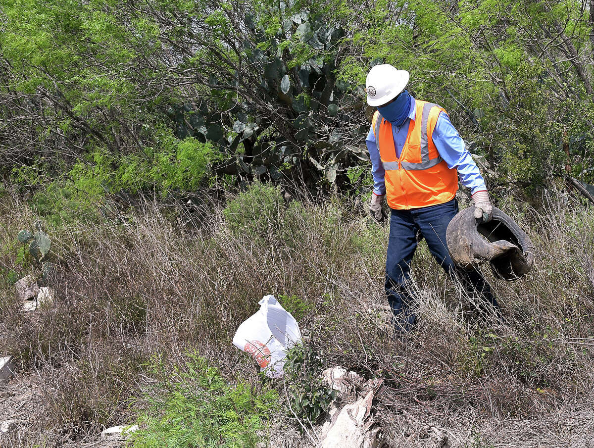 An employee of the Webb County Road and Bridge Department collects a discarded tire in the La Presa Colonia on March 12, 2019.