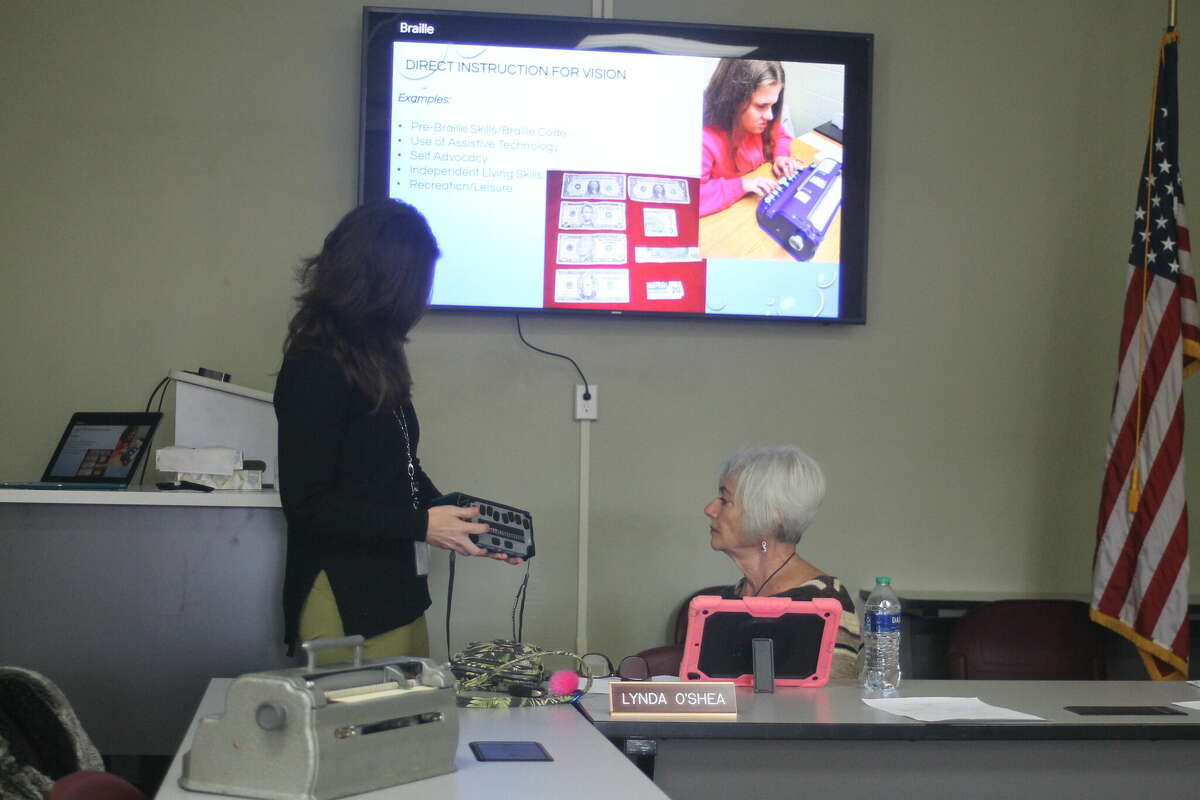 Sarah Stargardt, Manistee Intermediate School District teacher consultant for the visually impaired, shows Lynda O'Shea, Manistee ISD board secretary, a portable braille display March 21 during the Manistee ISD school board meeting.
