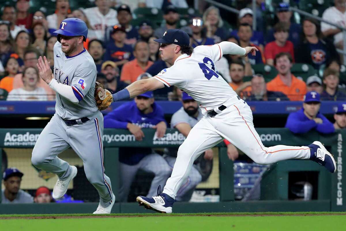Texas Rangers' Travis Grossman, left, is tagged out by Houston Astros third baseman Alex Bregman during the third inning of a baseball game Saturday, April 15, 2023, in Houston.