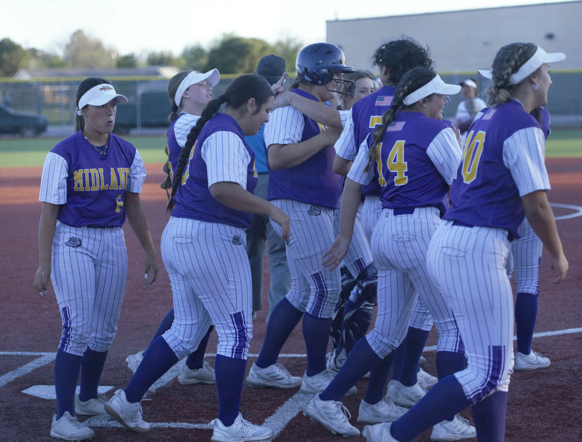 Midland High's Sadie Ryan, wearing a helmet, is greeted by her teammates after she hit a solo home run against Legacy, April 18 at Gene Smith Field. 