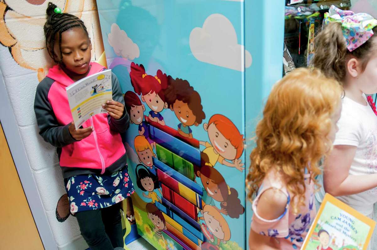 FILE - Janaya Sells, 7, reads a token-bought book on Sept. 26, 2019, during a ribbon cutting for an Inchy the Worm book vending machine at R.E. Stevenson Elementary School in Russellville, Ky. For decades, there has been a clash between two schools of thought on how to best teach children to read, with passionate backers on each side of the so-called reading wars. But the approach gaining momentum lately in American classrooms is the so-called science of reading. (Bac Totrong/Daily News via AP, File)