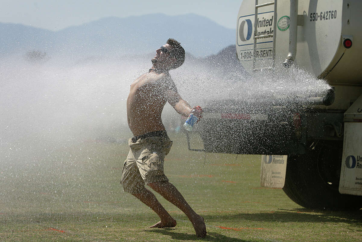 FILE: Beating the heat Thursday before the Coachella Valley Music and Arts Festival, Tony Lynch, 24, of Albany, New York, cools off behind a water truck after setting up his campsite on April 26, 2007.