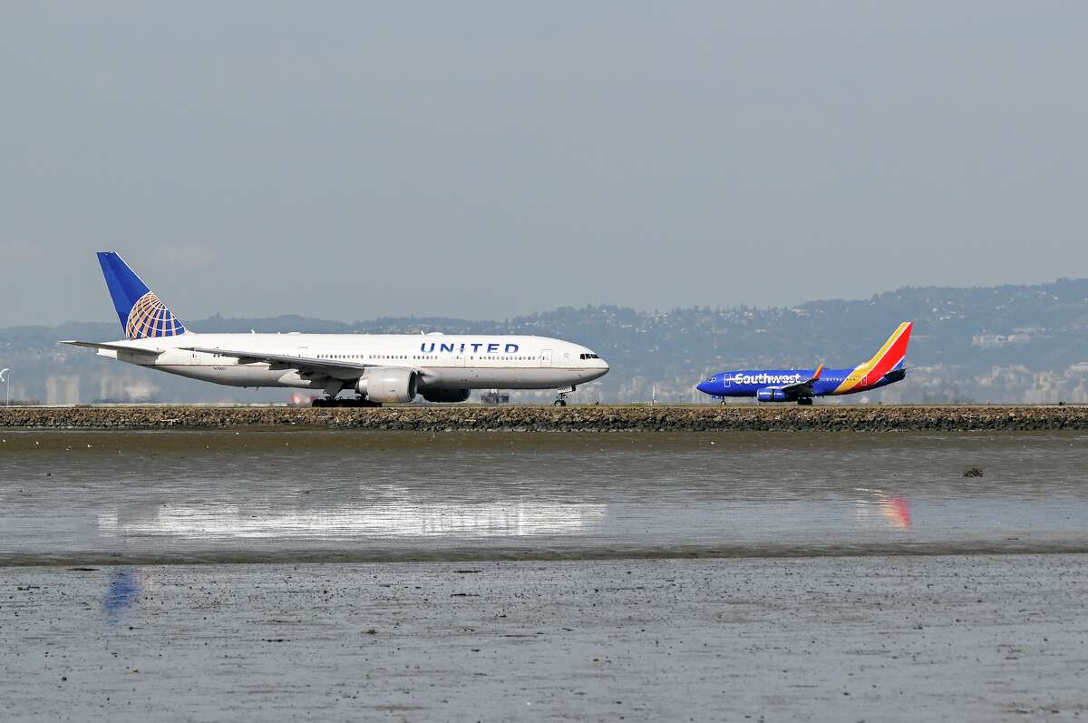 Bir United Airlines uçağı, Southwest Airlines uçağı 17 Mart 2023'te San Francisco'daki San Francisco Havalimanı'na inerken kalkışa hazırlanıyor.