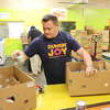 Damien Cope, Dunkin’s director of operations for the greater Beaumont and Houston areas, assembles canned foods into boxes on Friday, April 21, 2023, at the Southeast Texas Food Bank in Beaumont.