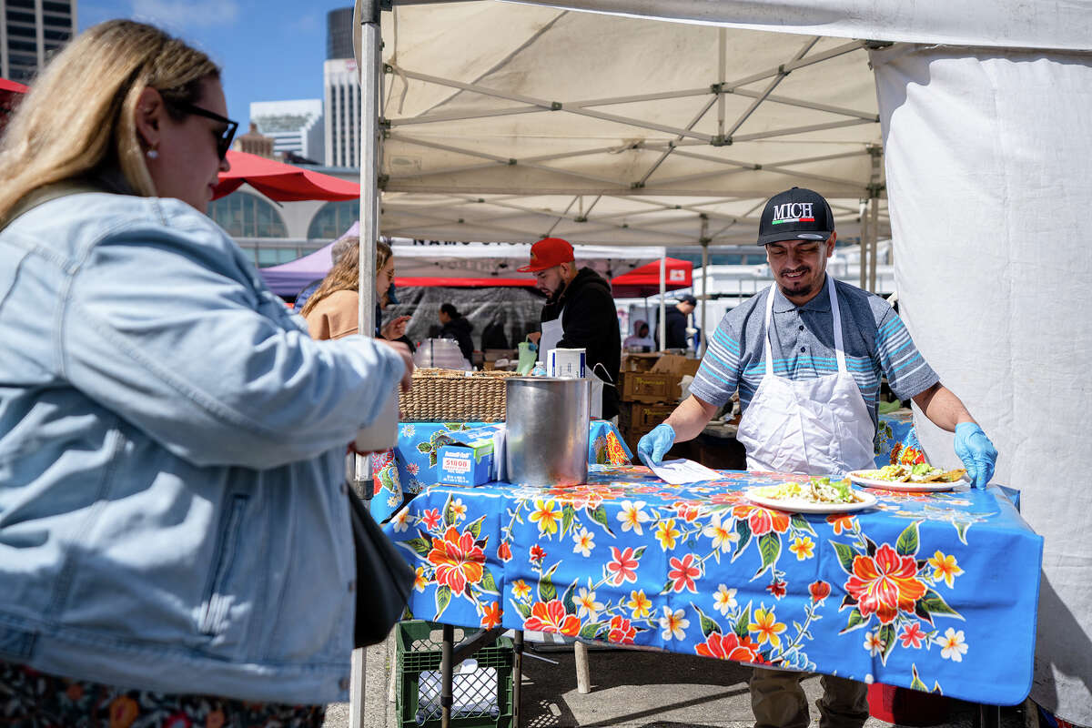 Employees deliver food to customers at the Primavera stall at the Ferry Building Farmer's Market on Saturday, April 15, 2023.