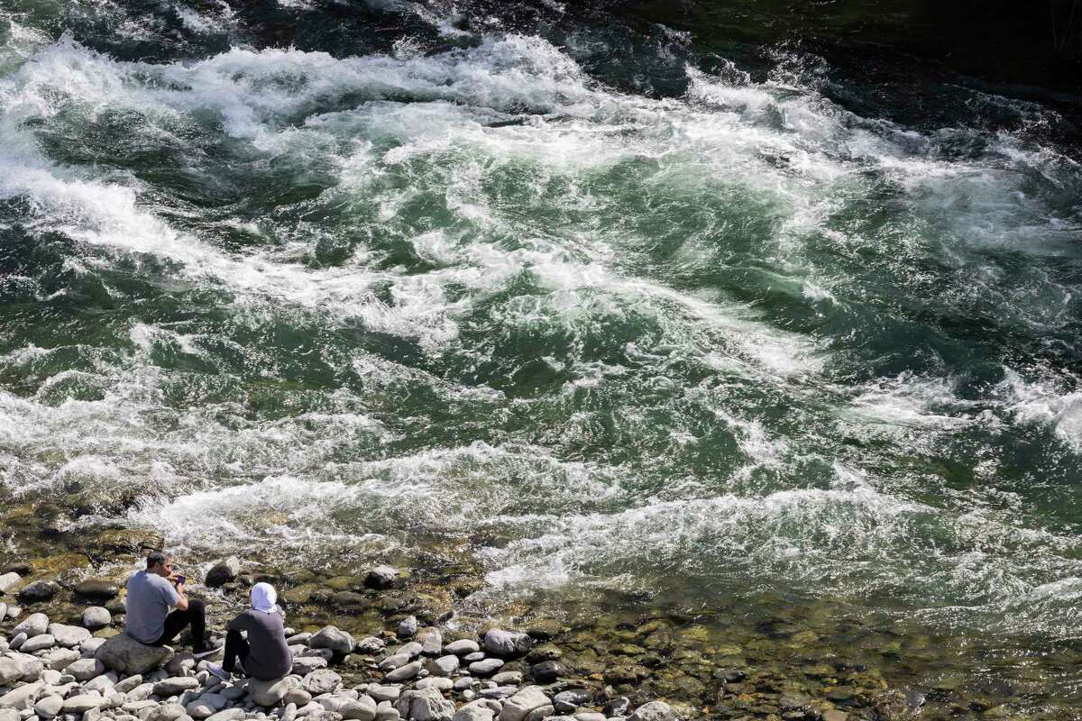 13日，在美国奥本州的奥本州立娱乐区，伊萨姆·拉菲(左)和妻子达琳正在观赏北福克美国河的白水。公共机构对该州大融化带来的危险的寒冷和快速的水保持警惕。